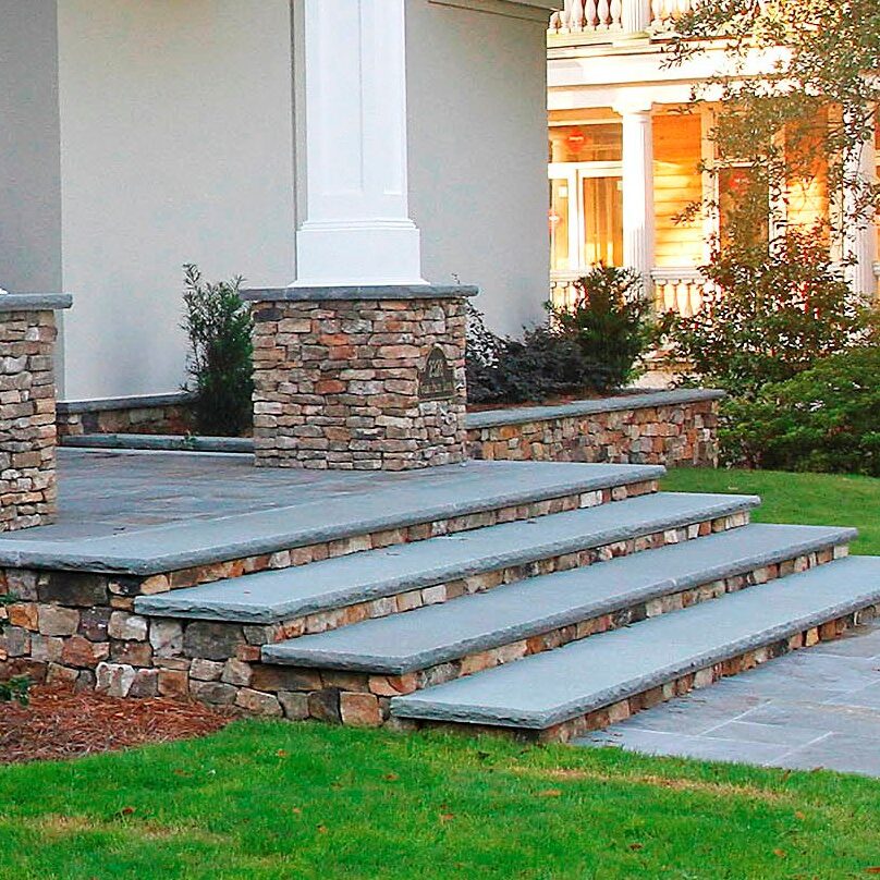 wide stone stairway, stone column bases, stone retaining wall at home entrance