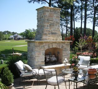 outdoor room featuring large stone fireplace with chimney overlooking a golf course
