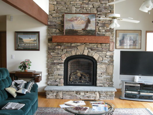 stone wall fireplace with raised hearth in living room