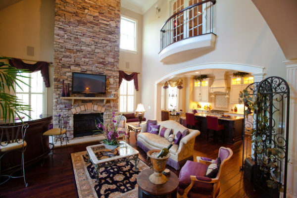 two-storey stone fireplace anchoring a living room, kitchen, bar area