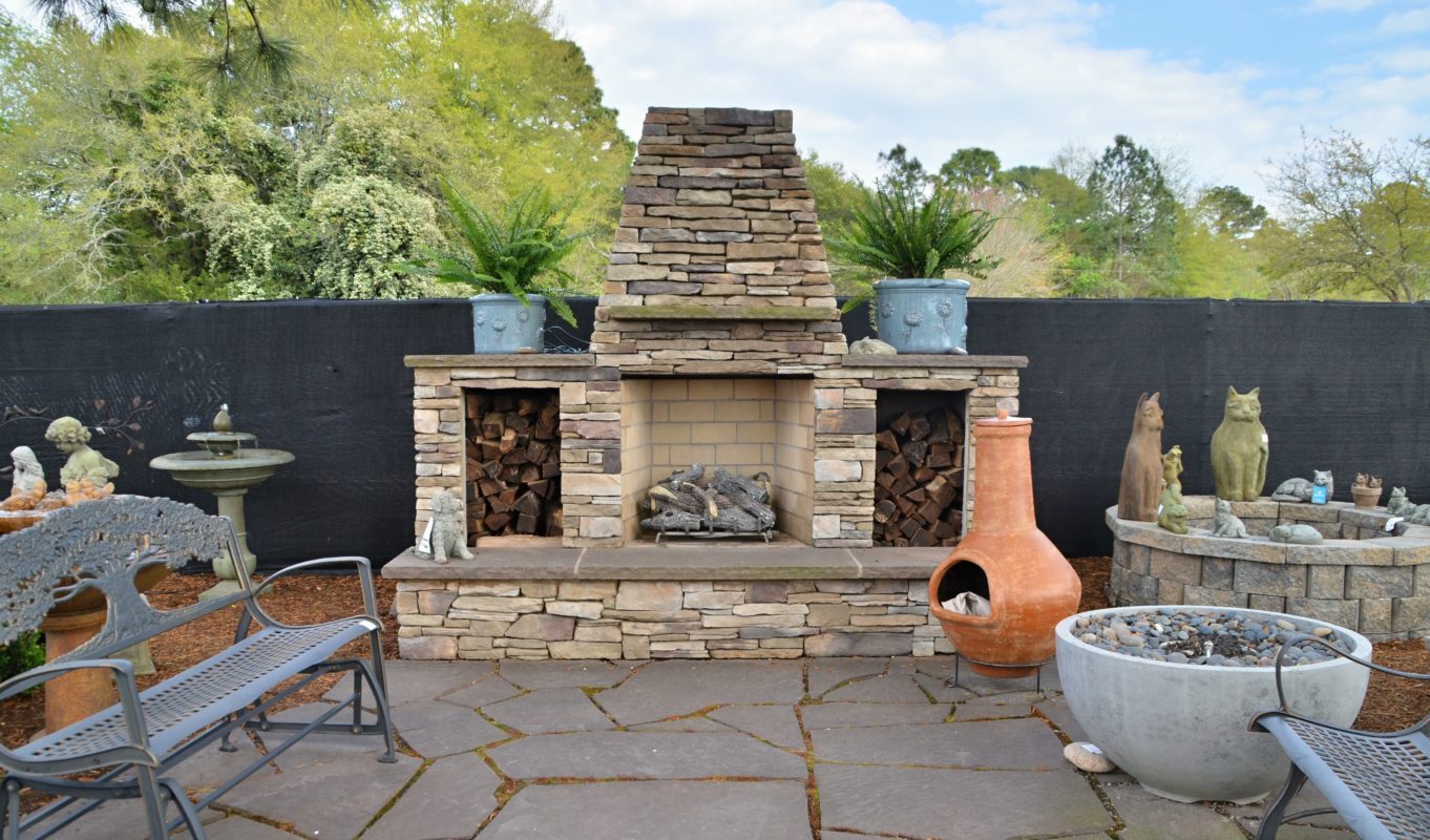 stone fireplace with a raised hearth, glazed plant pots, bird bath, bench, chiminea and garden art at stone garden