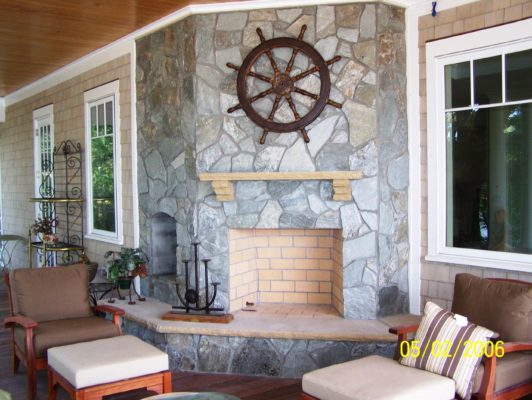 large, stone fireplace with raised hearth on a back porch
