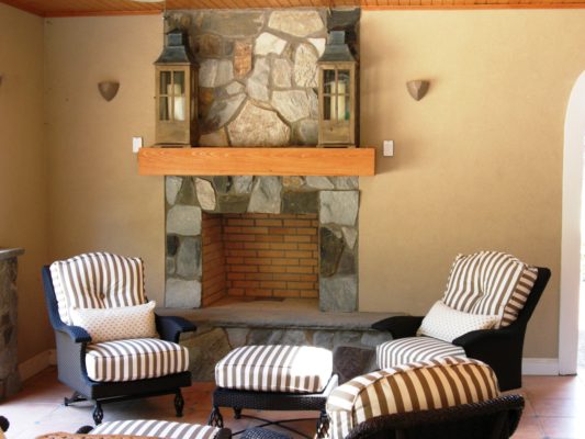 stone fireplace with raised hearth, wooden mantel, and candle lanterns in sun-room