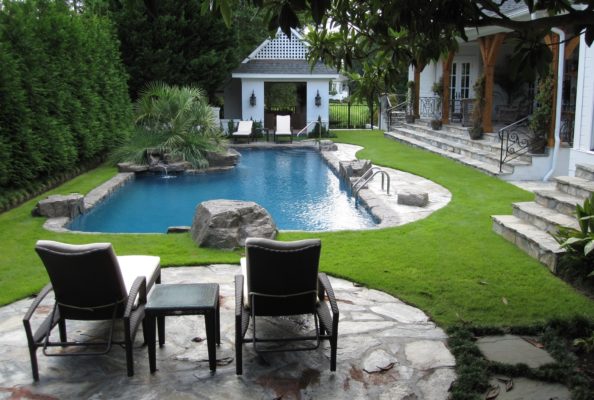 stone garden patio outdoor living area overlooking swimming pool, fountain, stone stairs and porch in backyward