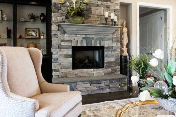 stone fireplace with raised bluestone hearth topped with wooden mantel in a living room