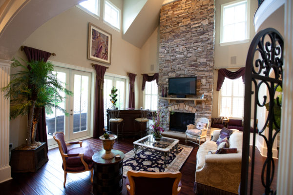 stone wall fireplace with raised hearth, stone mantel and TV in a two-storey living room