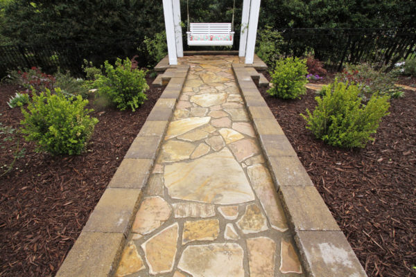 flagstone garden pathway leading to a swinging bench