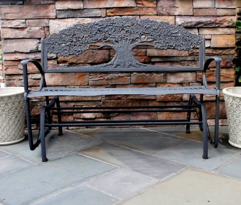 metal garden bench by stone wall on stone patio at stone garden