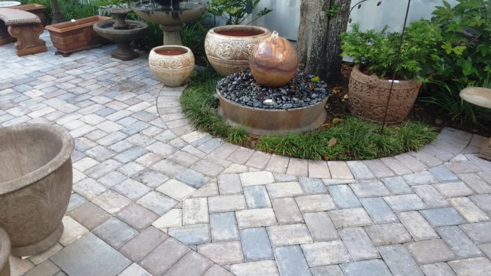 stone pavers patio, fountain, bench, and plant pot at stone garden display
