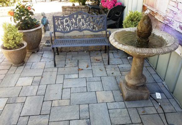 stone pavers patio, fountain, bench, and plant pot at stone garden display
