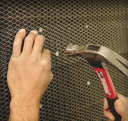 hand using hammer to nail into lath wire, a stone garden supply