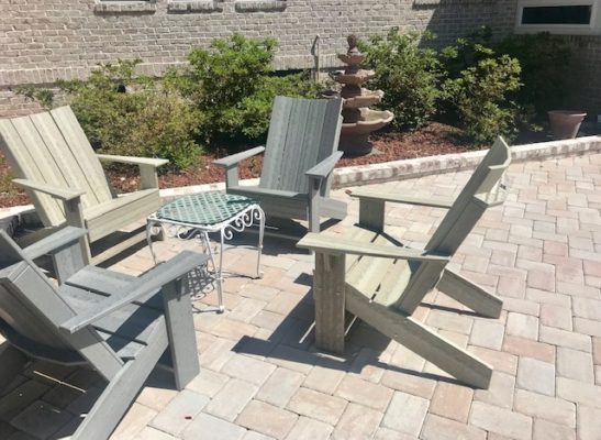 stone pavers patio with wooden chairs in garden with fountain