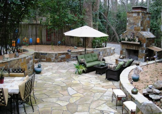 stone outdoor living room patio with fireplace and seating wall