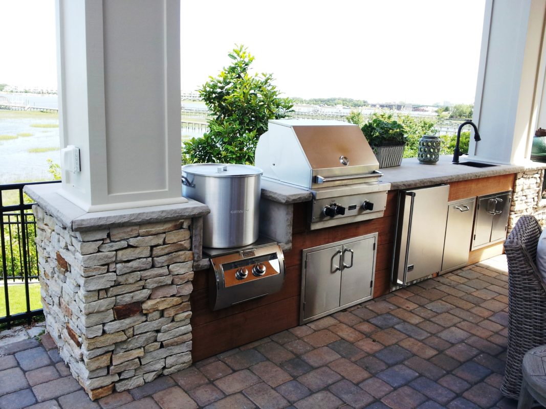 stone patio with outdoor living kitchen overlooking a waterway