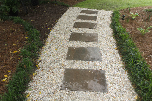 stepping stone garden pathway in rock gravel base bordered by mondo grass