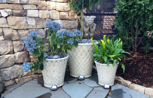 lattice planter pots on stone patio, gargoyle garden art sculpture and stacked stone wall