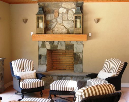 outdoor living room patio featuring stone fireplace