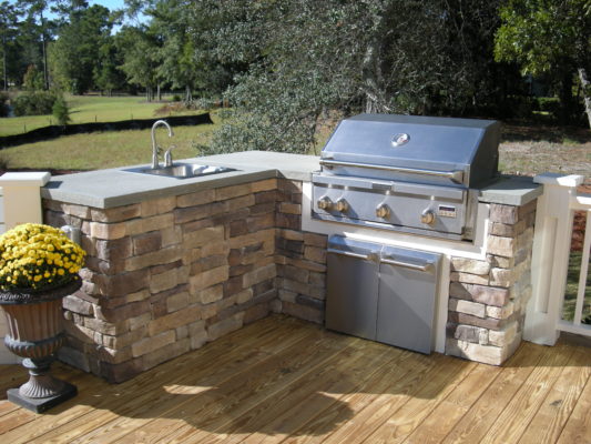 stone outdoor living kitchen with sink and grill cabinet