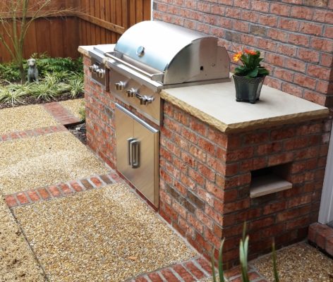 outdoor living kitchen featuring a sandstone top on a brick grill cabinet