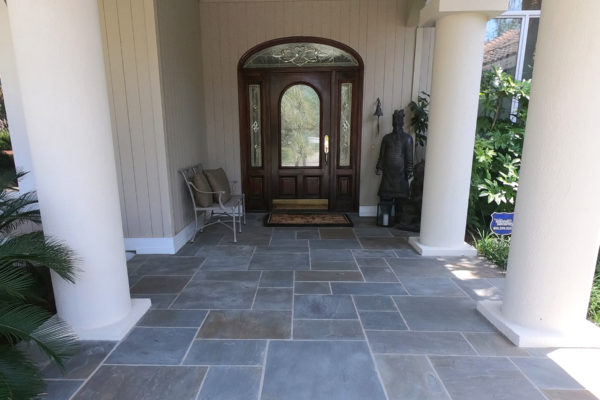 home entrance featuring patterned blue stone paver patio, oriental garden art and columns
