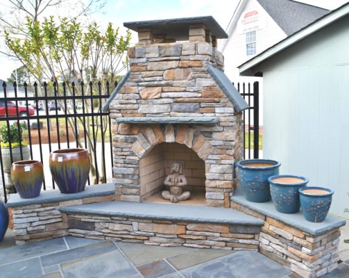 stone fireplace with a raised hearth, glazed plant pots and garden art at stone garden in wilmington north carolina