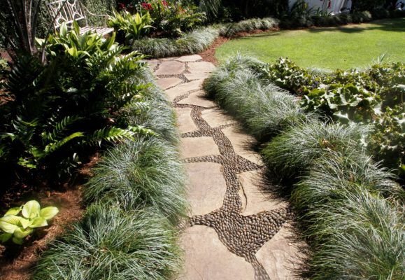flagstone garden pathway with mexican beach pebble joints and mondo grass border by a green lawn