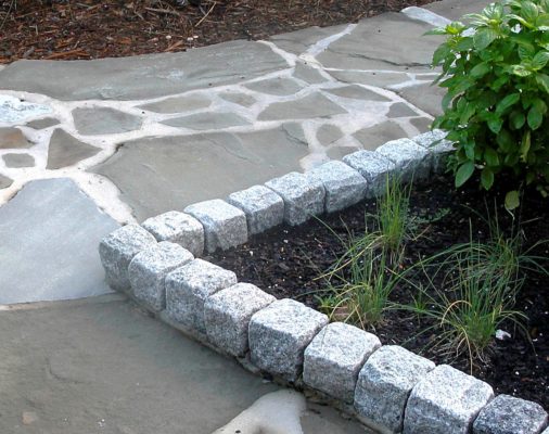 flagstone pathway with granite boulder block edges by a garden