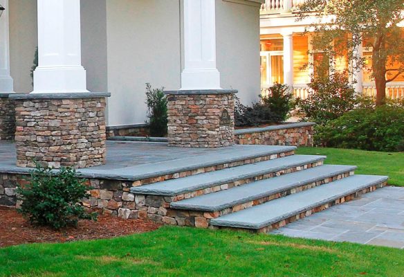 stone entrance steps, patio and retaining wall at the front of a home