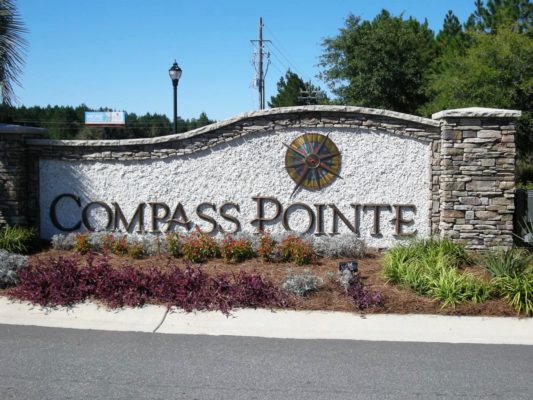 stone garden pillars and stone wall with business sign for Compass Pointe