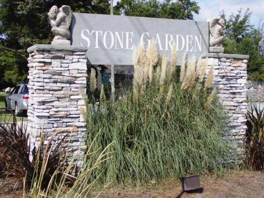 stacked stone columns hold up engraved sign for Stone Garden with gargoyle statuary