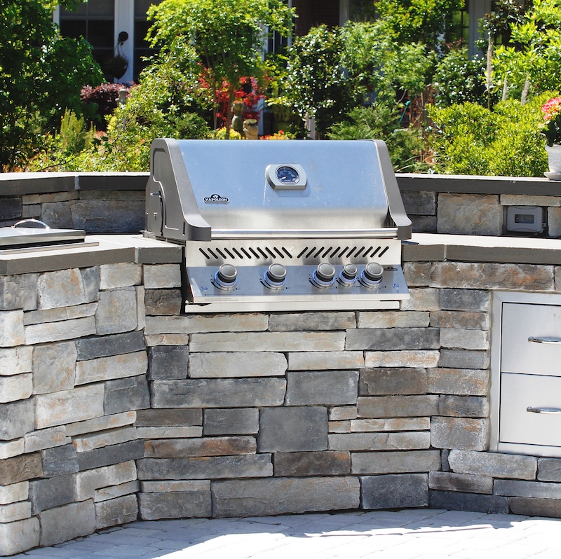 stone outdoor grill station in a backyard garden