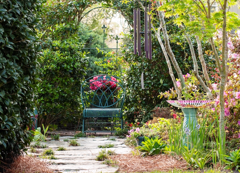 stone patio-iron seating-birdbath-green foliage-pink flowers