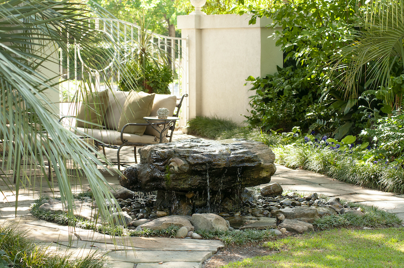 etched boulder fountain a flagstone patio in a back yard garden