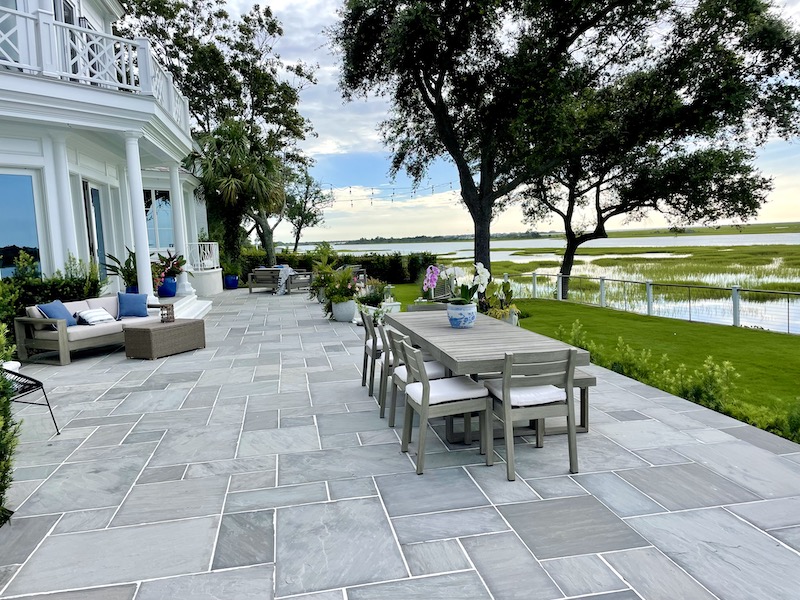 sterling gray sandstone patio with outdoor dining and living areas overlooking a peaceful waterway